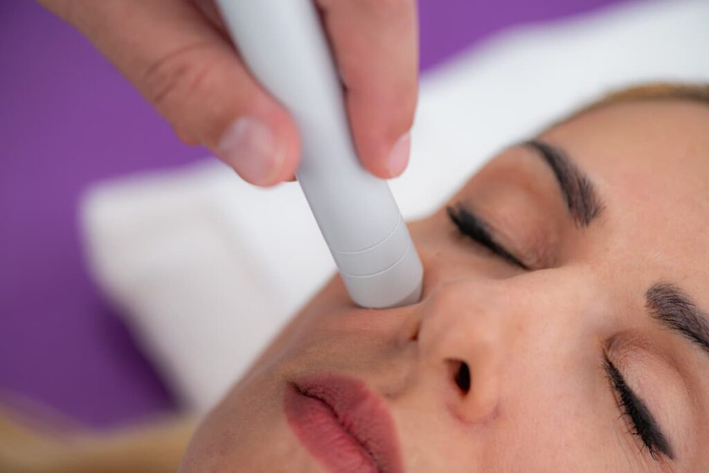Imagen de una mujer en Quito recibiendo una limpieza facial con punta de diamante en un consultorio dermatológico luminoso