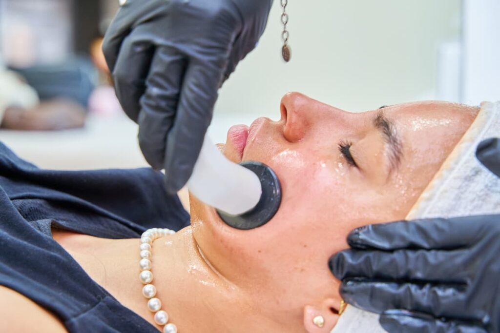 Paciente femenina relajada durante el procedimiento de limpieza facial con punta de diamante en la clínica Thaliderm