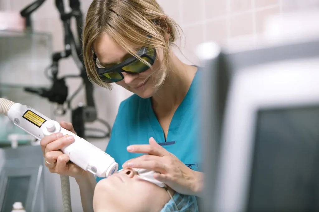 Doctora dermatóloga aplicando tratamiento de laser co2 fraccionado en las mejillas de una paciente en la clínica en Quito.