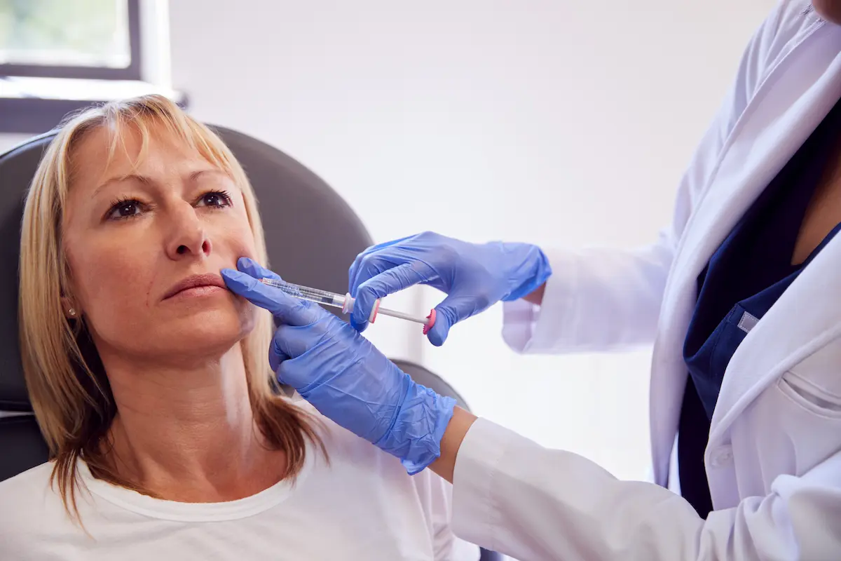 Dermatóloga aplicando Radiesse en el rostro de una paciente en una clínica especializada de Quito.