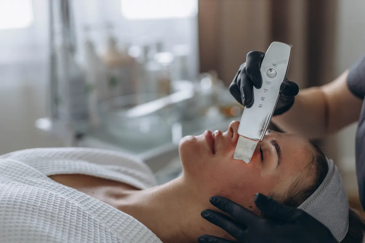 Dermatóloga aplicando un tratamiento con exosomas en el rostro de una paciente con dispositivo de micropunción
